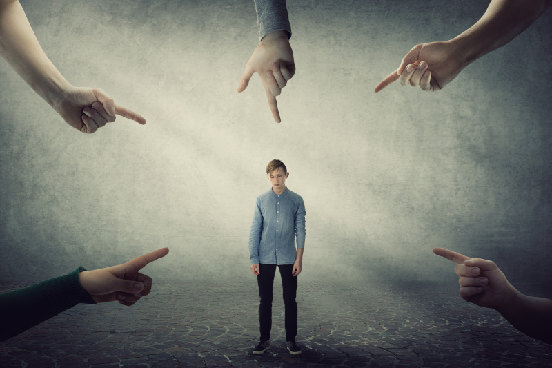 Stressed teen boy, under pressure, looking down feel ashamed and discomfort as lots of hands pointing index to him blaming as guilty. Upset student experiencing adolescence crisis, regret the mistake. Test Therapist